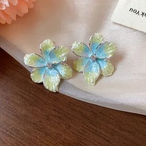 Détail de boucles d'oreilles fleurs en émail dégradé bleu et jaune avec zircon