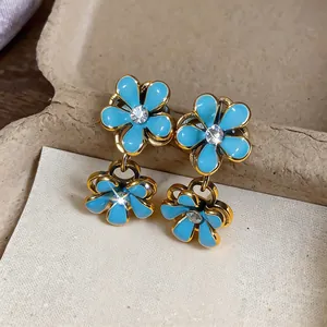 Close-up macro view of blue enamel flower earrings with sparkling rhinestone centers