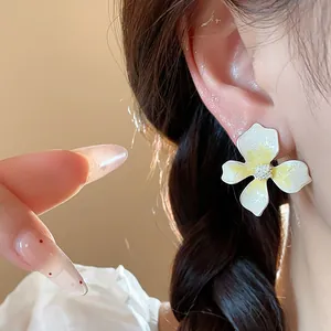 Macro view of elegant white and yellow enamel flower stud earrings on ear for a sweet look