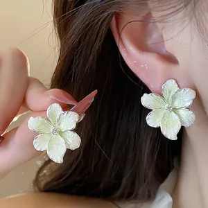 Gros plan détaillé d'élégantes boucles d'oreilles fleurs en émail jaune et zircon