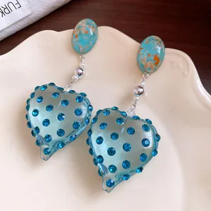 Close-up detail of vintage blue resin heart earrings with sparkling rhinestone studs