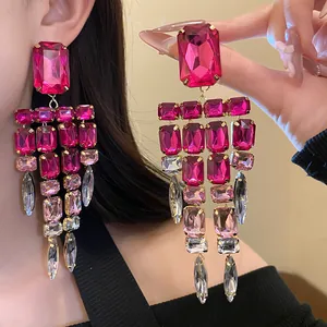 Close-up of oversized magenta crystal tassel earrings with sparkling multifaceted stones.