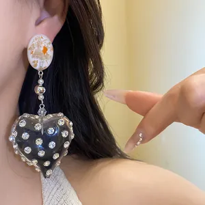 Detail shot of vintage heart-shaped resin earrings featuring elegant sparkling rhinestones