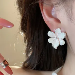 Boucle d'oreille fleur en émail blanc avec un centre en zircon étincelant sur l'oreille