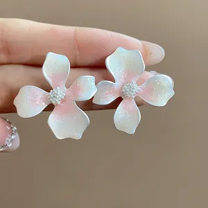 Detailed macro view of oil-drop flower stud earrings featuring pink gradient and glitter