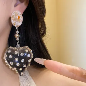 Macro view of vintage heart resin earrings with sparkling rhinestones and silver needles