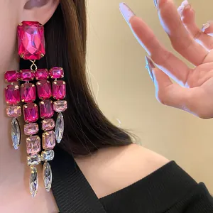 Detailed close-up of vibrant fuchsia square rhinestone tassel earrings on model ear