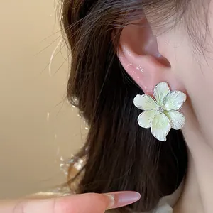 Détail d'une boucle d'oreille fleur blanche avec centre en cristal sur un modèle