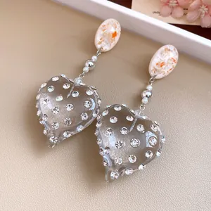 Detailed view of vintage resin heart earrings with shimmering rhinestones and silver pins