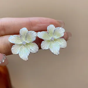 Vue détaillée de boucles d'oreilles fleurs en émail jaune scintillant et centre en zircon