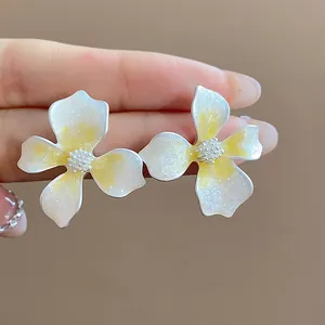 Close-up of sweet minimalist flower stud earrings with yellow oil-drop glitter finish