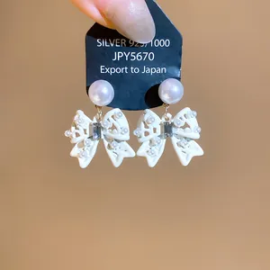 Dettaglio di orecchini a fiocco bianco in stile francese con perle e cristalli