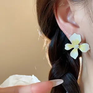 Elegant close-up of white and yellow enamel flower stud earrings with silver needles