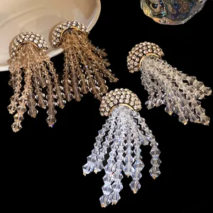 Macro detail of faceted crystal tassels and rhinestone-inlaid domes on silver needle earrings