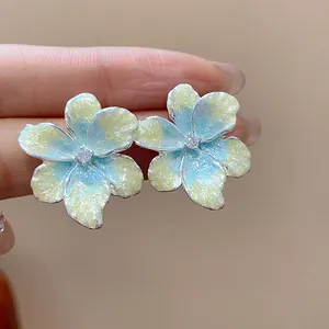 Vue détaillée de boucles d'oreilles fleurs en émail bleu et jaune avec centre en zircon