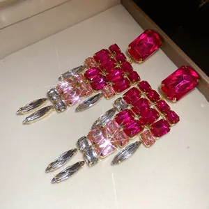 Close-up of sparkly pink square crystal tassel earrings with elegant gold setting