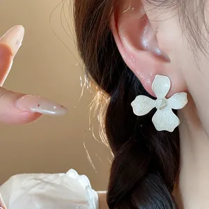 Close-up of elegant white flower stud earrings with detailed enamel finish on ear
