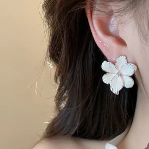 Gros plan détaillé d'un clou d'oreille fleur en émail blanc avec zircon au centre