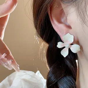 Macro detail view of elegant white flower stud earring with pink glitter on model's ear