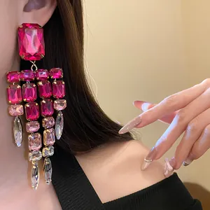 Detailed view of oversized pink crystal tassel earrings on model