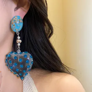 Vintage heart-shaped resin earrings with blue rhinestones on an Asian female model