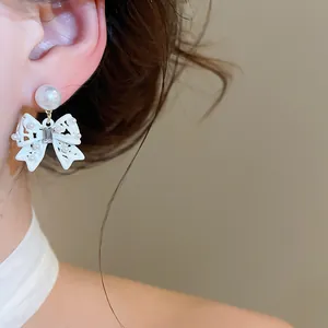 Primo piano dettagliato di eleganti orecchini a fiocco bianco con perle sull'orecchio