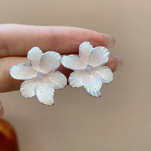Vue macro de boucles d'oreilles fleurs blanches chatoyantes avec centre en zircon brillant