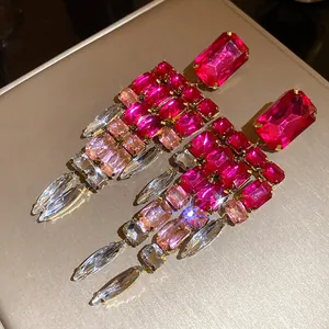 Detail of crystal tassel earrings with pink rectangular stones in gold setting.