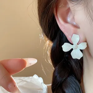 Detailed close-up of a sweet white flower stud earring worn on a female model's ear