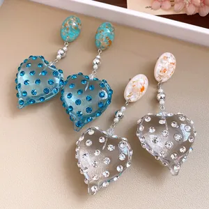Detailed close-up of vintage resin heart earrings with blue and clear rhinestones.