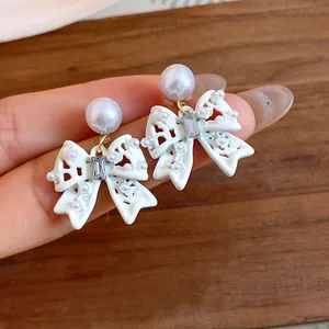 Dettaglio di eleganti orecchini a fiocco bianchi con perle e cristalli lucenti