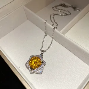 Macro detail of a star-shaped silver necklace with a brilliant yellow center stone.