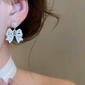 Primo piano di eleganti orecchini a fiocco bianco con perle delicate e cristalli