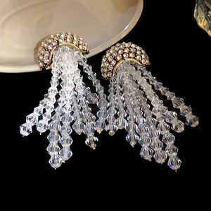 Detail view of sparkling silver needle earrings with rhinestone studs and crystal tassels.