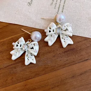 Dettaglio ravvicinato orecchini a fiocco bianchi con perle rosa e cristallo chiaro