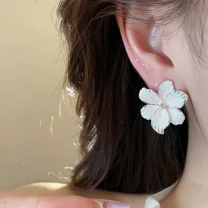 Gros plan d'une élégante boucle d'oreille fleur en émail blanc avec zircon au centre