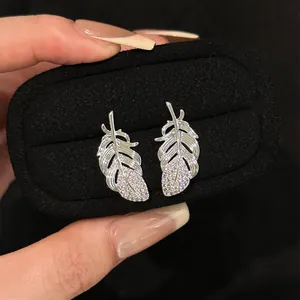 Close-up of elegant silver feather stud earrings with sparkling micro-inlaid stones