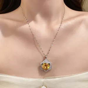 Close-up of a sparkling star pendant necklace with a yellow center stone on a model.