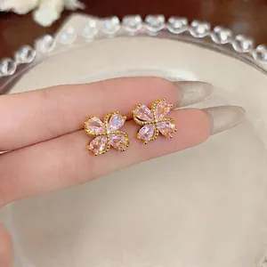 Elegante Kleeblatt-Ohrstecker mit rosa Zirkonia, präsentiert auf der Hand für Maßstab