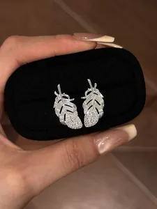Close-up of elegant silver feather stud earrings with sparkling rhinestones in black box