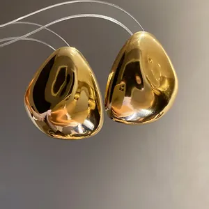 Detaillierte Nahaufnahme goldener geometrischer Ohrstecker mit polierter Spiegeloberfläche