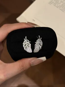 Detailed view of elegant silver feather stud earrings with sparkling rhinestones