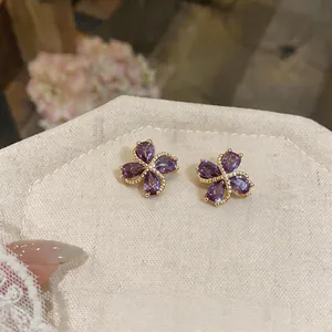 Elegante lila Zirkon Blumenstecker-Ohrringe mit Vergoldung auf beige Leinen-Stoff