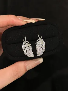 Exquisite silver feather stud earrings featuring micro-pave sparkling crystals in a black box.