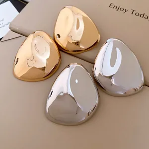 Detailansicht der übergroßen metallischen geometrischen Ohrstecker in Gold und Silber poliert