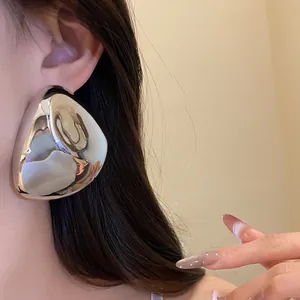 Detailansicht eines großen geometrischen silbernen Metall-Ohrrings am Ohr des Models