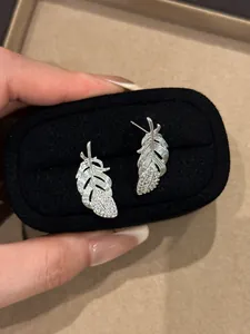 Close-up of elegant silver feather stud earrings with sparkling rhinestones in a box