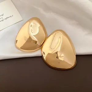 Nahaufnahme von polierten goldenen geometrischen Ohrsteckern mit hochglänzendem Metallfinish