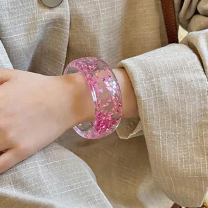Close-up of transparent pink resin bangle with heart glitter on a woman's wrist.