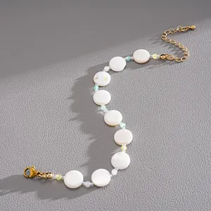 Detailed macro view of a minimalist shell beaded bracelet with golden adjustable chain